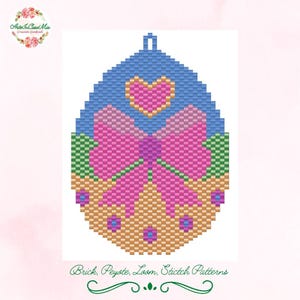 Può includere: Un ornamento per uovo di Pasqua a forma di uovo con un fiocco rosa, un cuore e foglie verdi. L'uovo è realizzato con perline blu chiaro, rosa, verde e arancio.