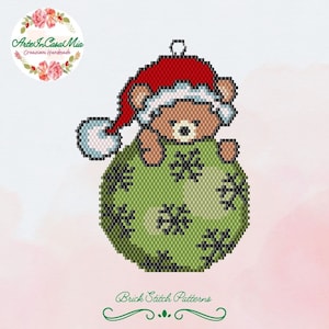 Può includere: Un ornamento natalizio verde con un orso marrone che indossa un cappello rosso di Babbo Natale. L'ornamento è decorato con fiocchi di neve bianchi. Brick Stitch Patterns.