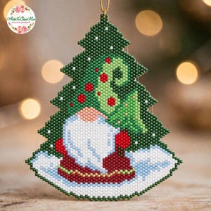 Può includere: Un addobbo natalizio in perline raffigurante uno gnomo con barba bianca e cappello rosso davanti a un pino verde scuro con accenti rossi e bianchi. Lo gnomo poggia su una base bianca innevata, il tutto realizzato con piccole perline uniformi.