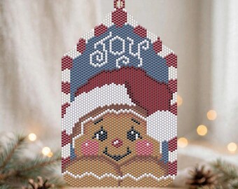May include: A rectangular beaded ornament featuring a gingerbread person wearing a red Santa hat with white trim. The word Joy is written in white script at the top against a blue background. The border has red and white stripes.