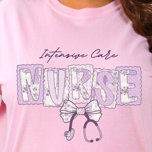 Puede incluir: Camiseta rosa claro con la frase "Intensive Care Nurse" en una fuente morada decorativa. La palabra "NURSE" tiene un diseño de patchwork con patrones florales y de lunares. Un lazo y un gráfico de estetoscopio están debajo.