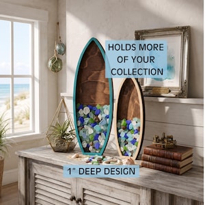 May include: Two surfboard-shaped wooden shadow boxes with a 1-inch deep design, featuring dark wood backings and teal or light wood frames, filled with assorted blue, green, and white sea glass, with text reading HOLDS MORE OF YOUR COLLECTION.