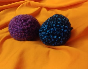 Puede incluir: Dos bolas de crochet, una morada y otra azul con motas negras, sobre una superficie naranja brillante.