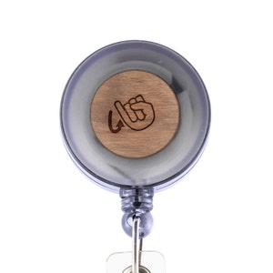 May include: A black retractable badge holder with a wooden insert featuring a hand sign for "I love you" in American Sign Language.