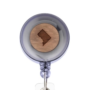 May include: A black retractable badge holder with a wooden disc featuring a laser-engraved outline of the District of Columbia.