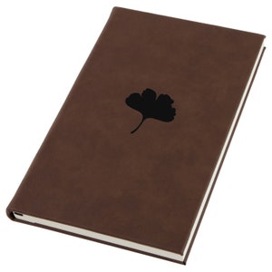 May include: A brown leather-bound journal with a black ginkgo leaf design on the front cover.