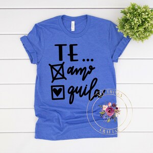 May include: A royal blue t-shirt with a black graphic that says "TE...amo, quila" with a tick and a heart in front of the words.