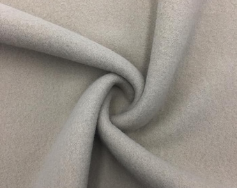 May include: A close-up of a light gray fabric with a soft, fuzzy texture. The fabric is folded and draped, showing its drape and texture.