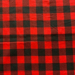 May include: Red and black buffalo plaid fabric. The fabric has a woven texture.