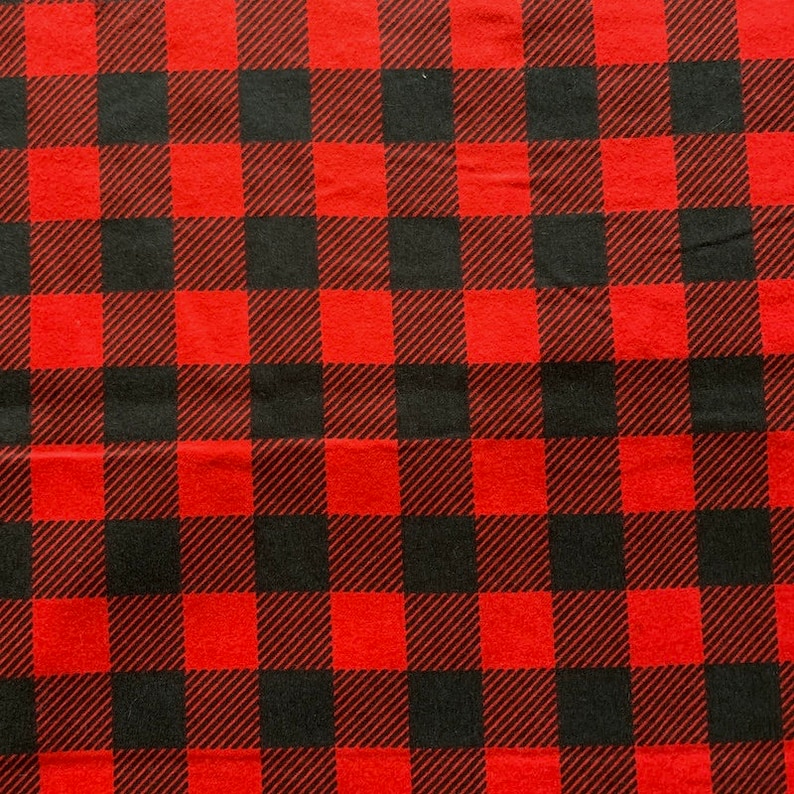 May include: Red and black buffalo plaid fabric. The fabric has a woven texture.