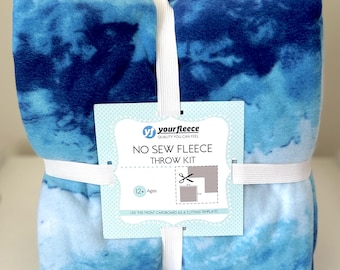 May include: A no-sew fleece throw kit in shades of blue, tied with white elastic and ribbon. The kit includes two fleece blankets with a tie-dye effect and a tag that reads "yourfleece" and "NO SEW FLEECE THROW KIT".
