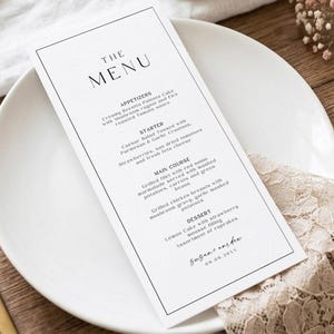 May include: A tall, rectangular white menu card with a thin black border and black serif text. The menu lists appetizers, starters, main courses, and desserts, featuring the names Susan and Andrew with the date 09.09.20XX at the bottom.