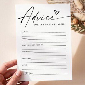 Könnte beinhalten: Eine weiße, rechteckige Hochzeits-Ratgeberkarte mit schwarzem Text, der Advice FOR THE NEW MRS. & MR. lautet, sowie einem kleinen Herzsymbol. Die Karte enthält sechs Zeilen zum Ausfüllen mit den Beschriftungen Always, Never, Sometimes you need to, Don't forget, Babies are, I wish und With love.
