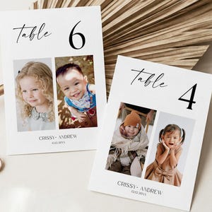 May include: Two white rectangular table number cards featuring the text Table 6 and Table 4 in black serif and script fonts. Each card displays two color photographs of children and the text CRISSY ANDREW 12.12.20XX at the bottom of the cards.