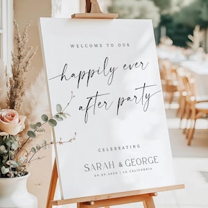Może przedstawiać: Biały prostokątny znak powitalny na ślub na drewnianej sztaludze. Tekst brzmi: WELCOME TO OUR happily ever after party CELEBRATING SARAH & GEORGE 09.09.20XX | LA CALIFORNIA. Znak jest wyświetlany obok wazonu z suszoną trawą pampasową i różą.