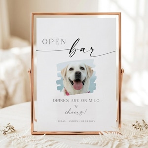 May include: A rectangular sign in a copper-colored metal frame featuring the text OPEN BAR, DRINKS ARE ON MILO, and cheers! with a central photograph of a light-colored dog. The bottom includes the text SUSAN + ANDREW | 09.09.20XX.
