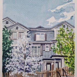 Op de afbeelding: Waterverf schilderij van een huis met een wit houten hek en een bloeiende boom in de voortuin. Het huis is grijs met witte versiering en heeft een veranda met een deur. De lucht is blauw met witte wolken.