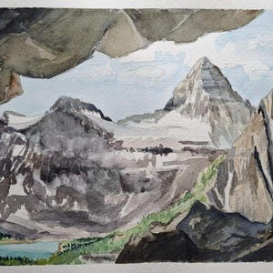 Op de afbeelding: Waterverf schilderij van een bergketen met een grote piek in het midden. De bergen zijn geschilderd in grijstinten en wit, met een klein meer op de voorgrond. De lucht is lichtblauw met witte wolken.