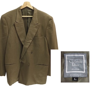 Puede incluir: Una chaqueta marrón de doble botonadura con una etiqueta que dice "Christian Dior, Monsieur, Sportswear, L".