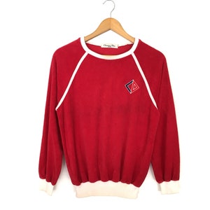 Può includere: Felpa a maniche lunghe rossa con bordini bianchi e un piccolo logo ricamato che dice "Christian Dior" sul davanti.