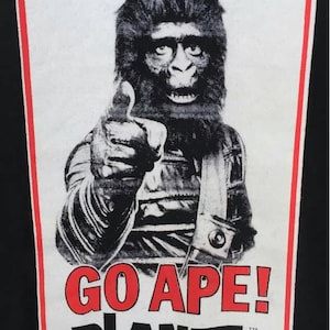 May include: Black t-shirt featuring a vintage Planet of the Apes movie poster. The poster has a red and white border with the text "20th Century Fox Wants You To... GO APE!" and an ape character giving a thumbs up.