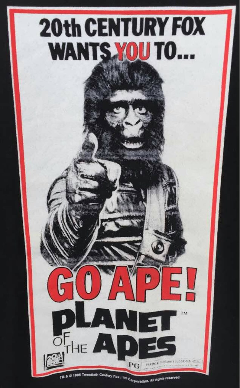 May include: Black t-shirt featuring a vintage Planet of the Apes movie poster. The poster has a red and white border with the text "20th Century Fox Wants You To... GO APE!" and an ape character giving a thumbs up.