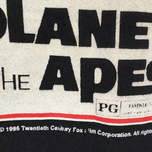 May include: Close-up of a black and white Planet of the Apes graphic. The text reads "PLANET OF THE APES" in large black letters. Below the text is a red and white stripe. The image also includes the PG rating and copyright information.