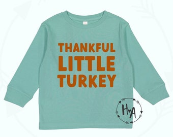 May include: A light blue long-sleeved shirt with the text "Thankful Little Turkey" in orange lettering.