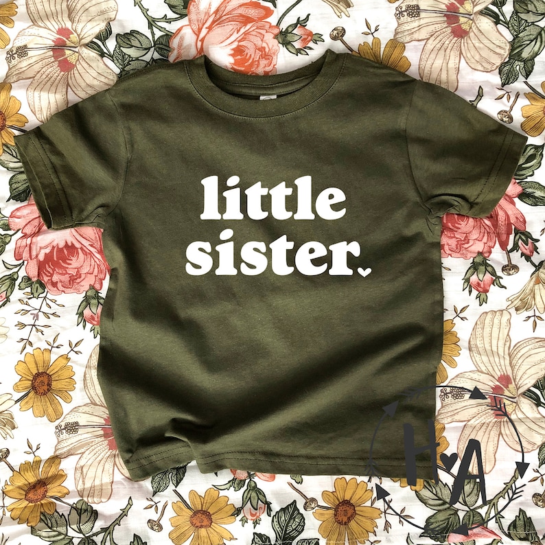 May include: A green t-shirt with the text "little sister" in white letters.