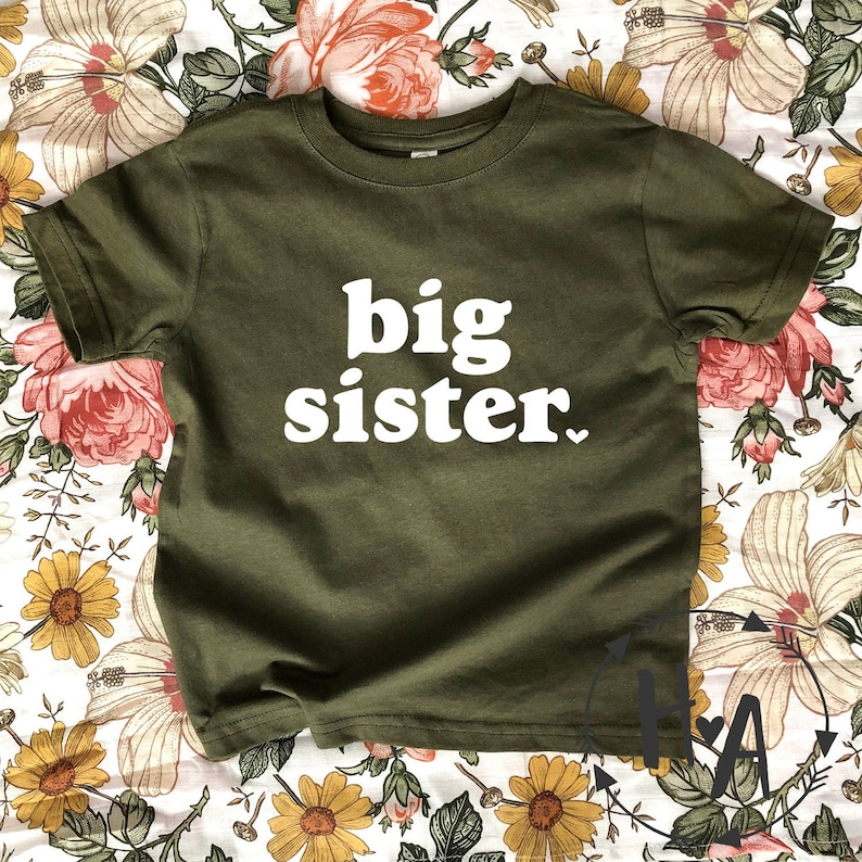 May include: A green t-shirt with the text "big sister" in white letters.