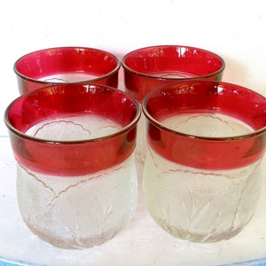 Puede incluir: Juego de cuatro vasos de vidrio esmerilado con borde rojo. Los vasos tienen un diseño texturizado y son perfectos para servir bebidas.