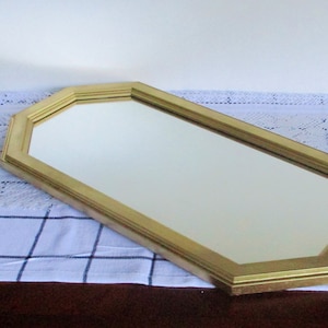 May include: A gold-colored octagonal mirror with a beveled edge.