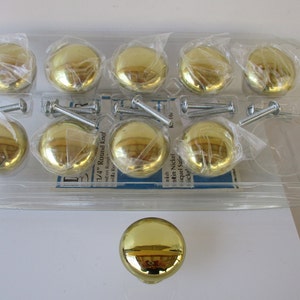 May include: A package of ten 1 1/4 inch round brass cabinet knobs with screws. The knobs are shiny and have a polished finish. The package is clear plastic and shows the knobs and screws.
