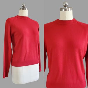 Puede incluir: Un suéter rojo de manga larga con cuello redondo y mangas raglán.