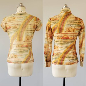 May include: A short-sleeved and a long-sleeved shirt with a colorful abstract print featuring a sunset, palm trees, and a rainbow. The shirt is made of a lightweight fabric and has a button-up collar.