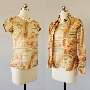 May include: A two-piece outfit with a short-sleeved shirt and a long-sleeved shirt. Both shirts feature a colorful abstract pattern with a rainbow design and a sunset scene. The fabric has a textured woven look.