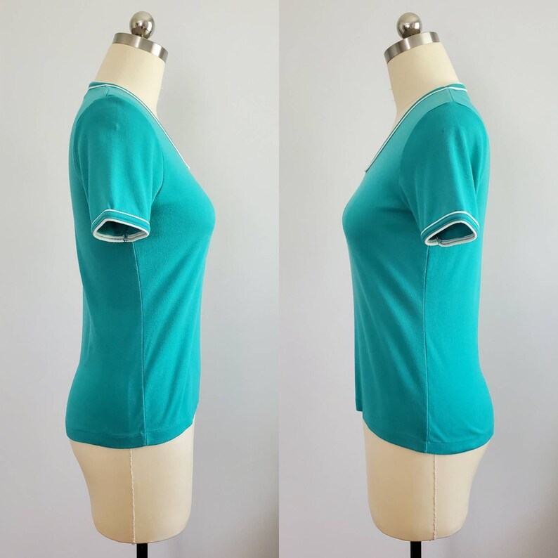 May include: A turquoise short-sleeved shirt with white trim around the neckline and sleeves.