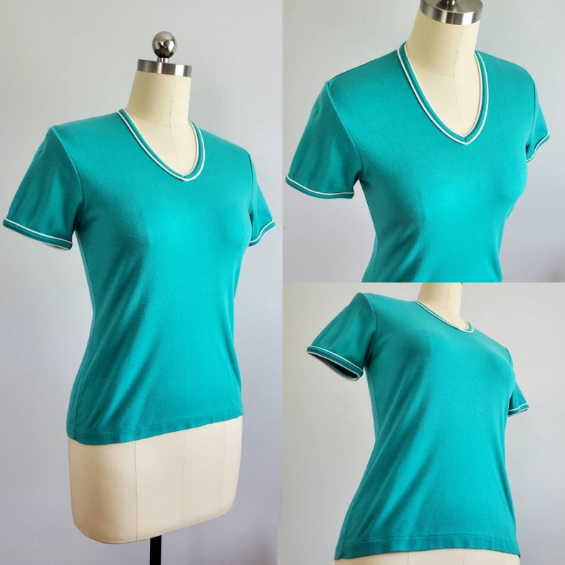 May include: A turquoise short-sleeved t-shirt with a white trim around the neckline and sleeves.