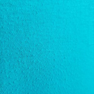 May include: A close-up of a turquoise fabric with a textured surface.