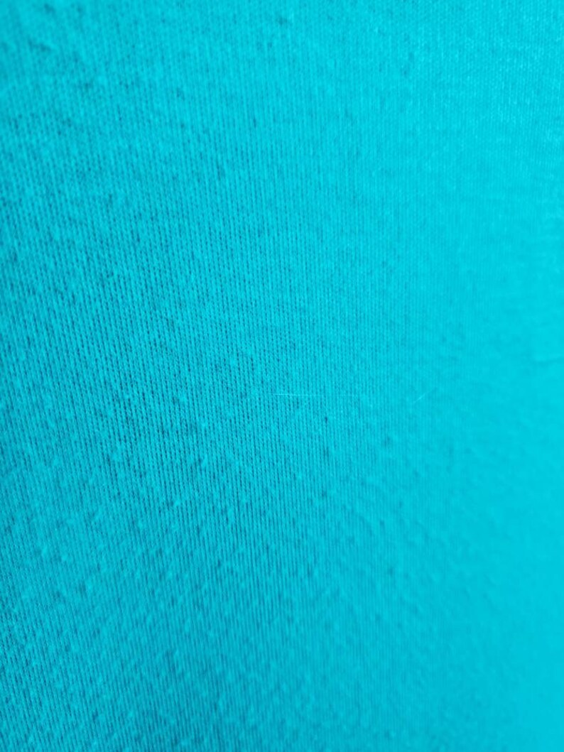 May include: A close-up of a turquoise fabric with a textured surface.