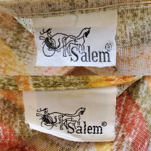 May include: Two white fabric labels with a black and white image of a horse-drawn carriage and the word "Salem" in black text. The labels are on a fabric background with a floral pattern in shades of orange, yellow, and green.