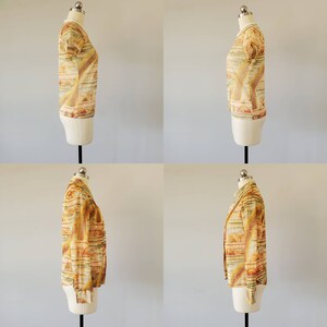 May include: A yellow and orange patterned blouse with a short sleeve and a crew neck. The blouse is on a white mannequin.