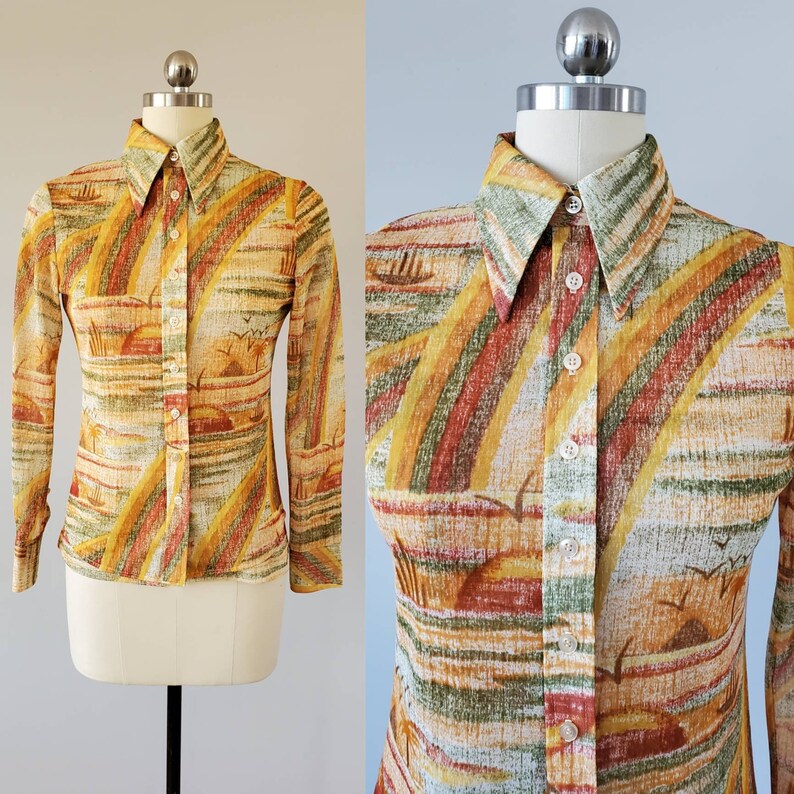 May include: A long-sleeved button-down shirt with a colorful abstract print featuring shades of yellow, orange, red, green, and brown. The shirt has a pointed collar and a button-up front.