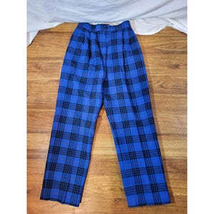 May include: Blue plaid pants with a classic pattern. The pants feature a high waist and a straight leg cut. The plaid design includes black and red lines over a bright blue background. The pants are made of a woven fabric.