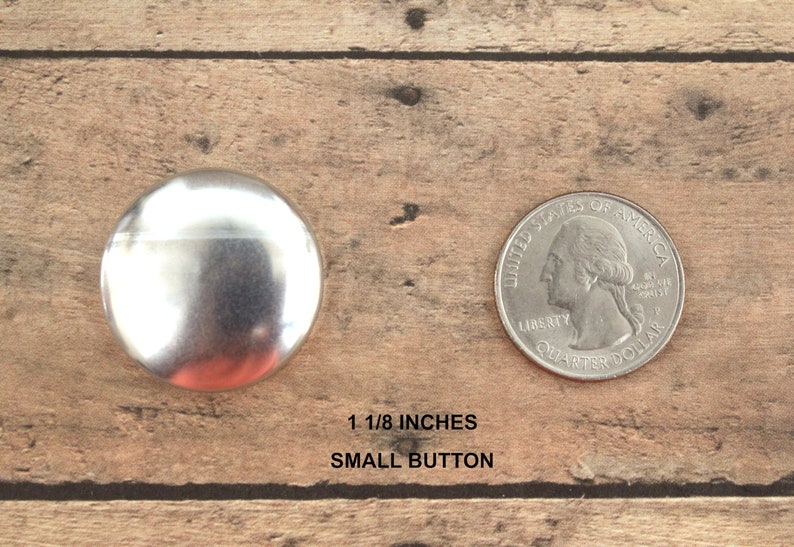 Pu&ograve; includere: Un bottone in metallo argentato di 3 cm di diametro, accanto a una moneta da 25 centesimi di dollaro americano per il confronto delle dimensioni. Bottone piccolo.
