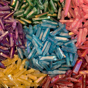 May include: An assortment of colorful quartz crystals in shades of green, pink, blue, purple, yellow, and red. The crystals are arranged in a circular pattern, with each color sectioned off. The crystals have a shimmering, iridescent quality.