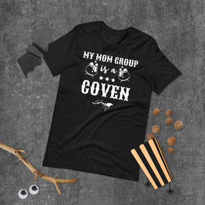 May include: Black t-shirt with white text that reads "My Mom Group is a Coven" with two white cauldron illustrations.