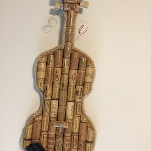 Pu&ograve; includere: Un violino realizzato interamente con tappi di sughero per vino. Il corpo, il manico e i piroli sono tutti costruiti con tappi di sughero. I tappi sono etichettati con vari marchi e nomi di vini.