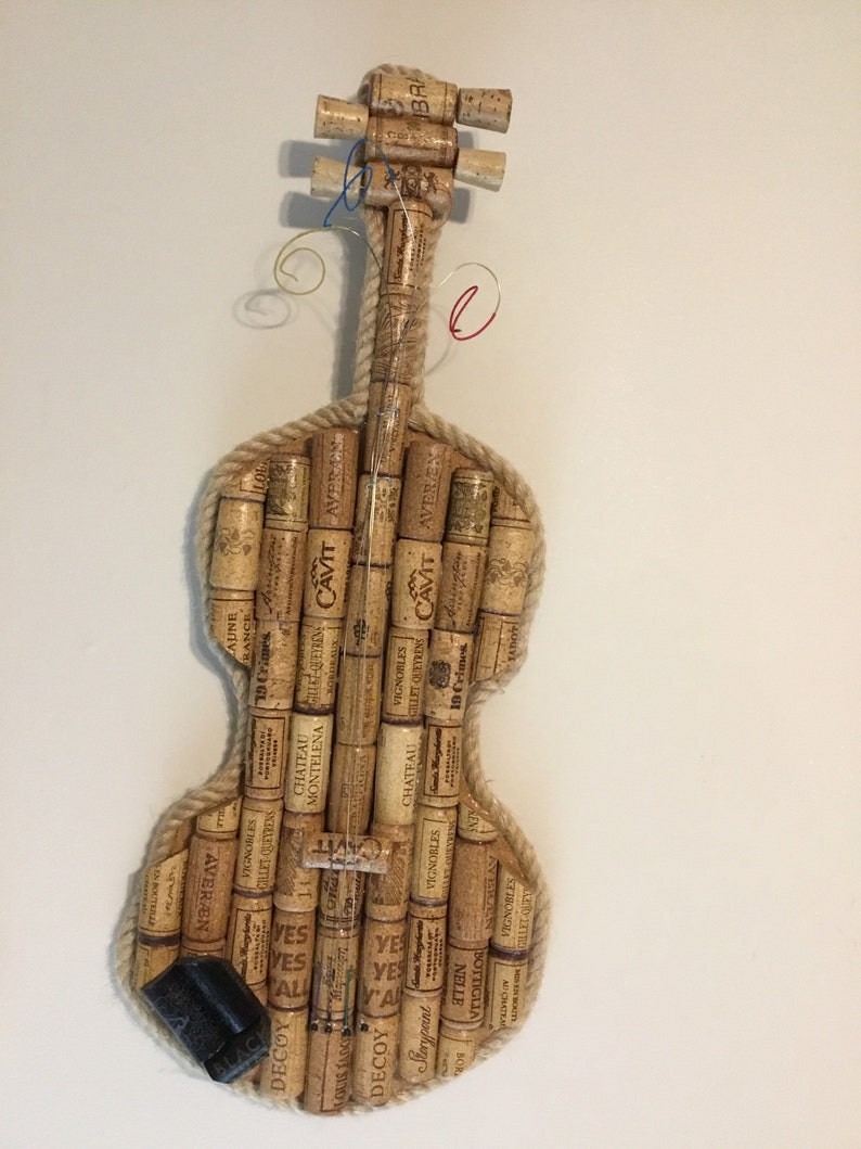 Pu&ograve; includere: Un violino realizzato interamente con tappi di sughero per vino. Il corpo, il manico e i piroli sono tutti costruiti con tappi di sughero. I tappi sono etichettati con vari marchi e nomi di vini.