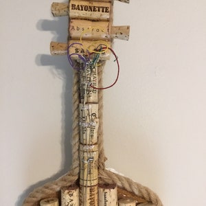 Pu&ograve; includere: Una chitarra realizzata con tappi di sughero per vino, con le parole "The Prisoner", "Bayonette", "Abstrac", "SA", "Chateau Monteena", "Delini", "Educated Guess", "Bayonett", "Banshee", "Morgan", "23 14" e "Bayonet" sui tappi. La chitarra &egrave; realizzata con un corpo in corda e ha un manico in legno.